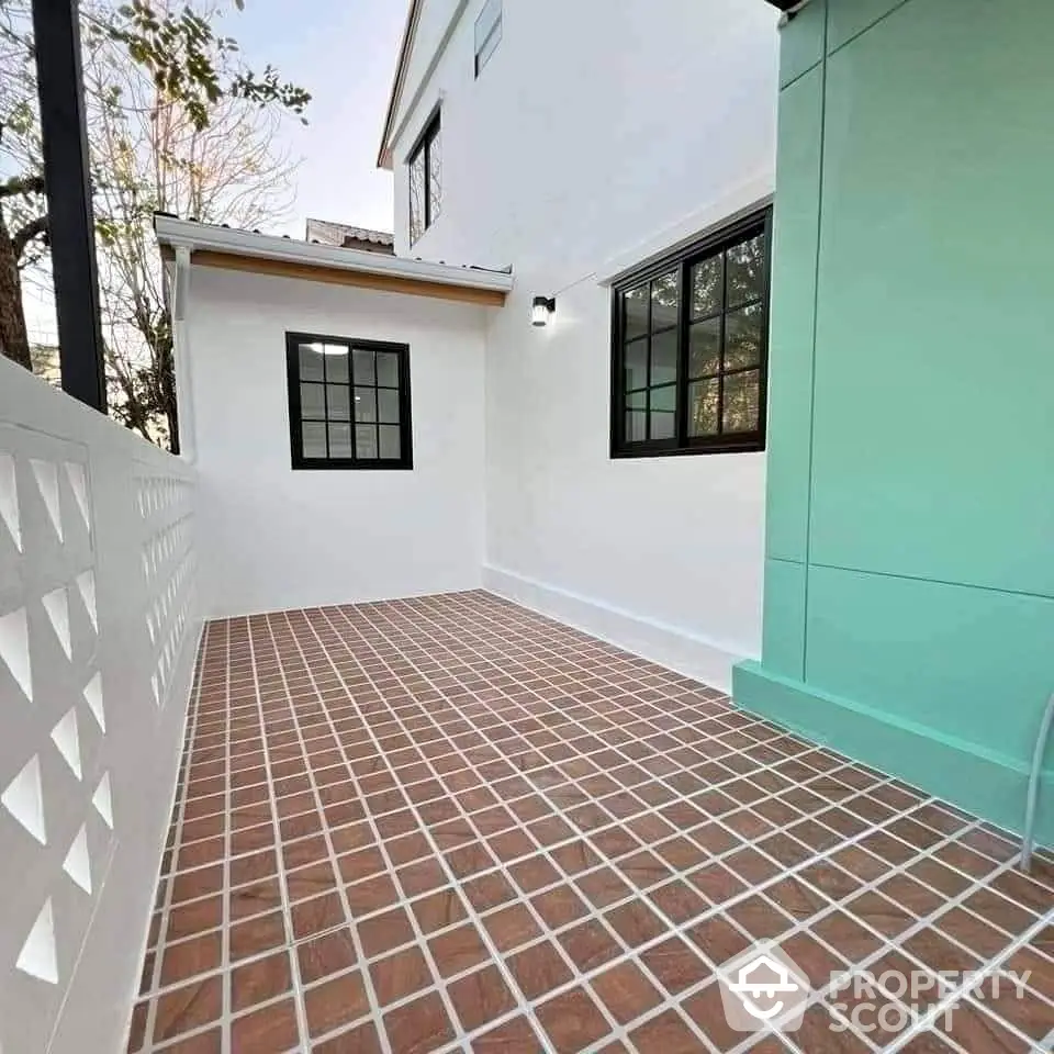 Charming outdoor patio with tiled flooring and modern white facade, perfect for relaxation and entertaining.