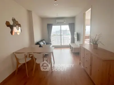 Modern living room with wooden flooring, stylish furniture, and city view from large window.