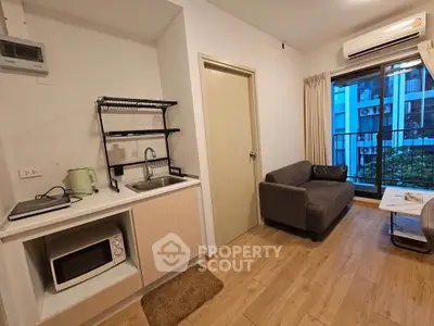 Modern studio apartment with compact kitchen and cozy living area, featuring a balcony with city view.