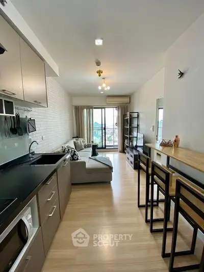 Modern open-plan living room with kitchen, stylish decor, and large windows offering a city view.