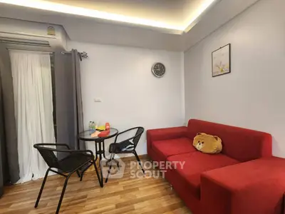 Cozy living room with red sofa, dining table, and wall clock, perfect for relaxation and entertaining.