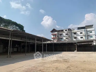 Spacious open industrial area with adjacent building under clear blue sky.
