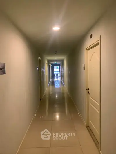 Spacious apartment corridor with polished tile flooring and bright lighting.