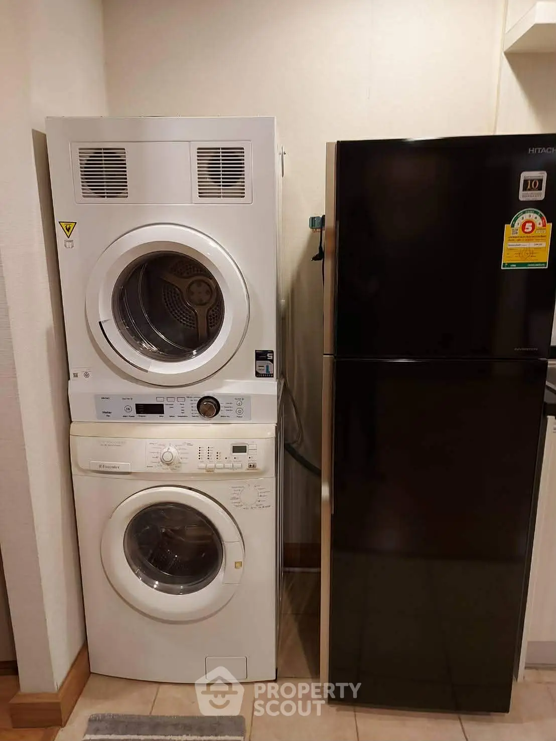 Modern laundry area with stacked washer and dryer next to a sleek refrigerator.