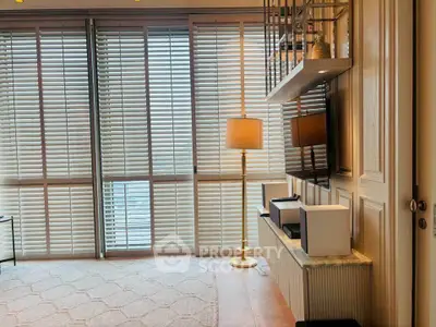 Spacious living room with modern decor and large windows with blinds, perfect for natural light.