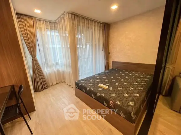 Cozy bedroom with modern furnishings and large windows for natural light.