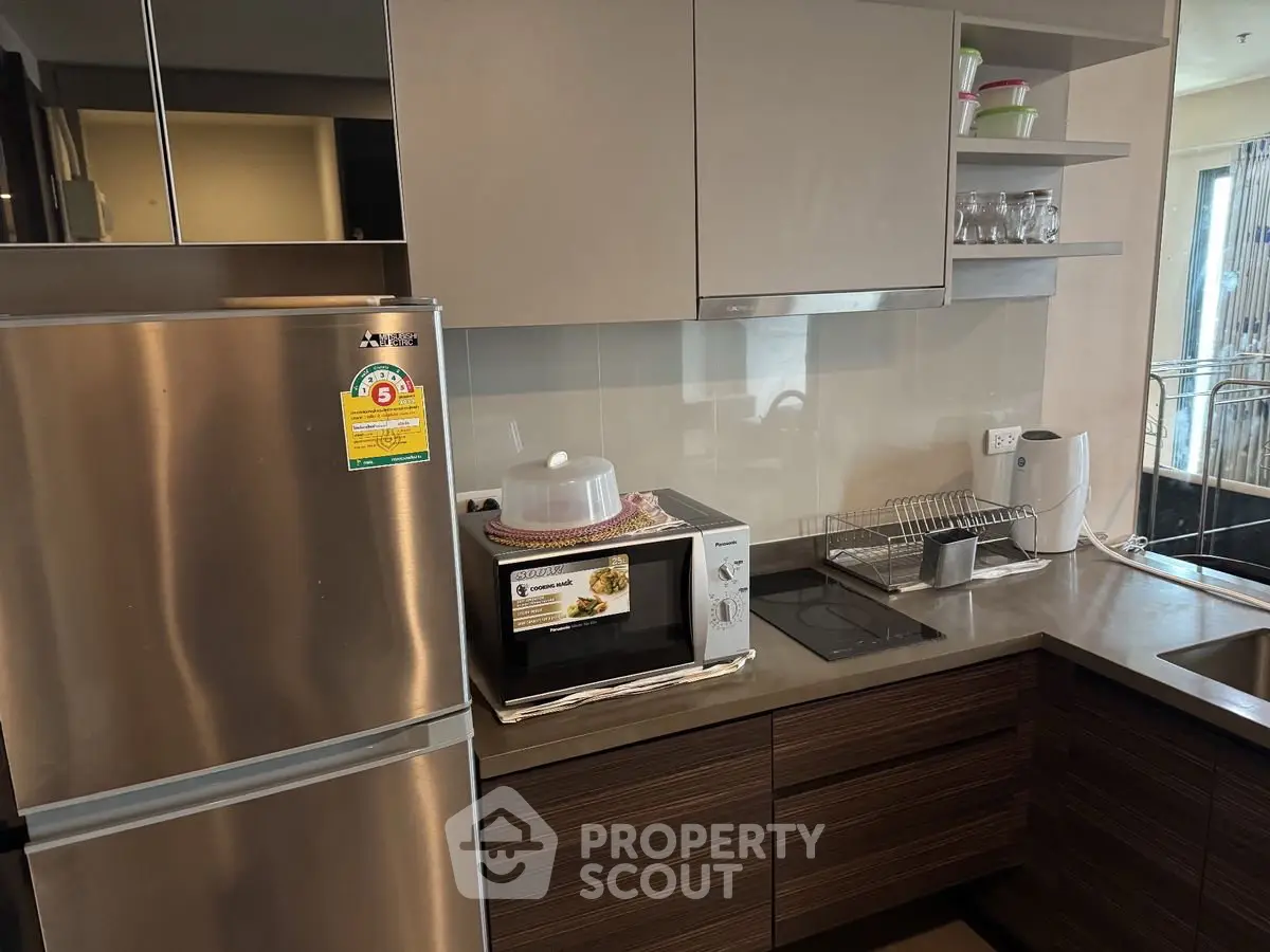 Modern kitchen with stainless steel fridge and microwave in sleek apartment