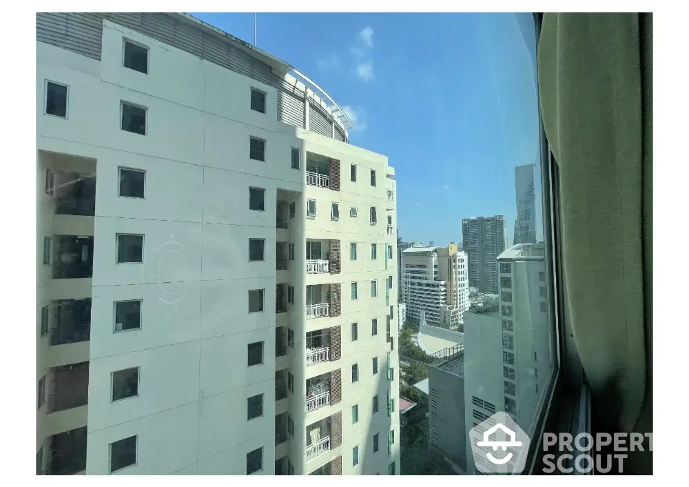 Stunning city view from high-rise apartment window showcasing urban skyline.