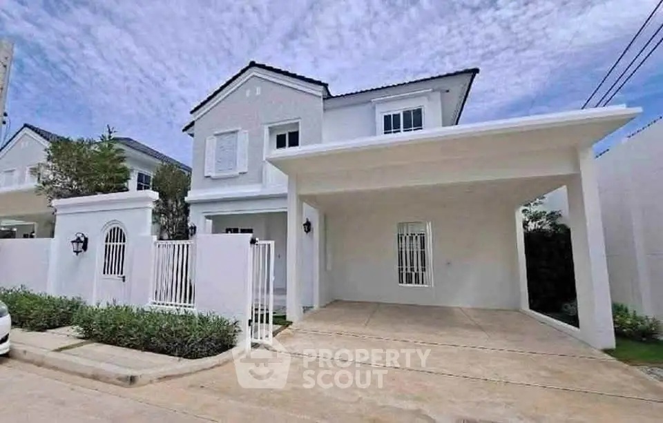 Charming two-story white house with spacious driveway and elegant gated entrance.