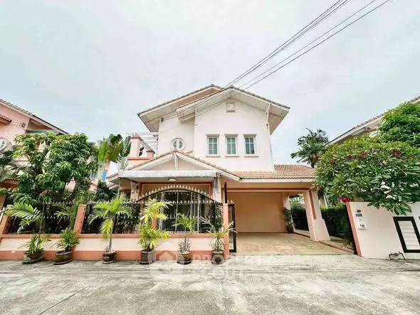 Charming two-story house with gated driveway and lush greenery in a serene neighborhood.