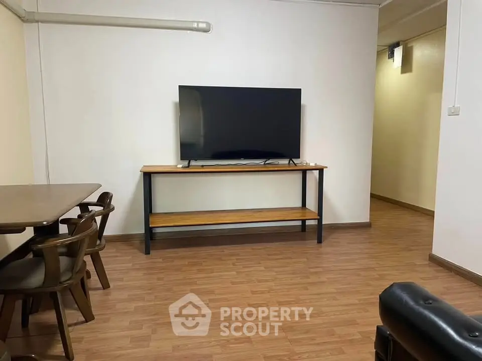 Spacious living room with modern TV setup and wooden flooring, perfect for relaxation and entertainment.