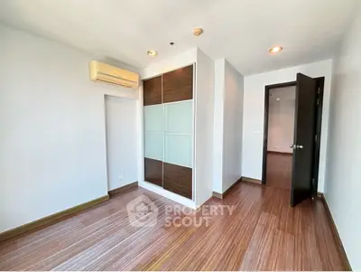 Spacious empty room with wooden flooring and built-in wardrobe, perfect for customization.