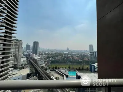 Expansive cityscape view from a high-rise balcony showcasing urban living at its finest, with clear skies and modern architecture.