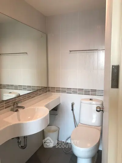 Modern bathroom with sleek fixtures and large mirror in a contemporary home.