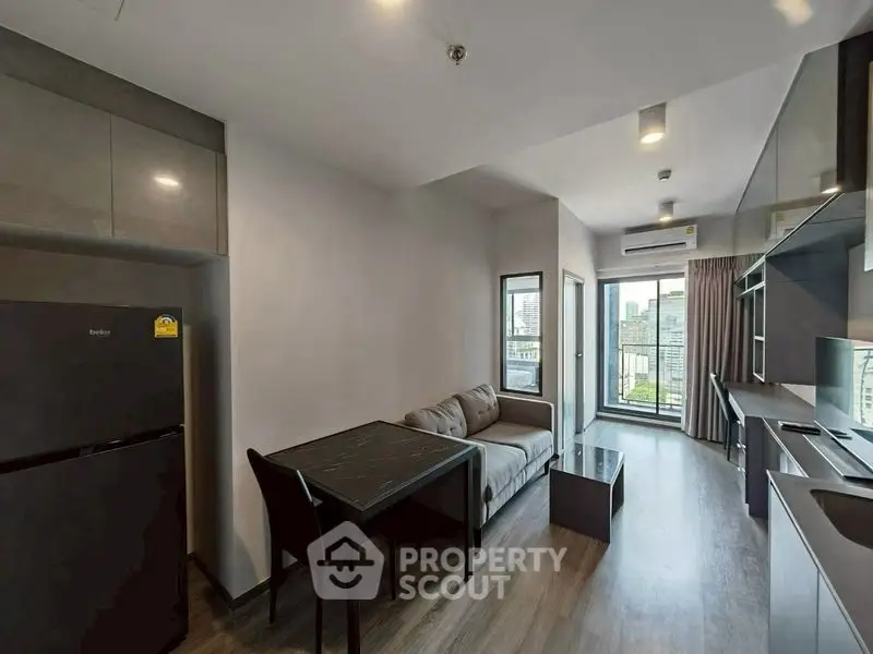Modern living room with city view, sleek furniture, and open kitchen layout in urban apartment.