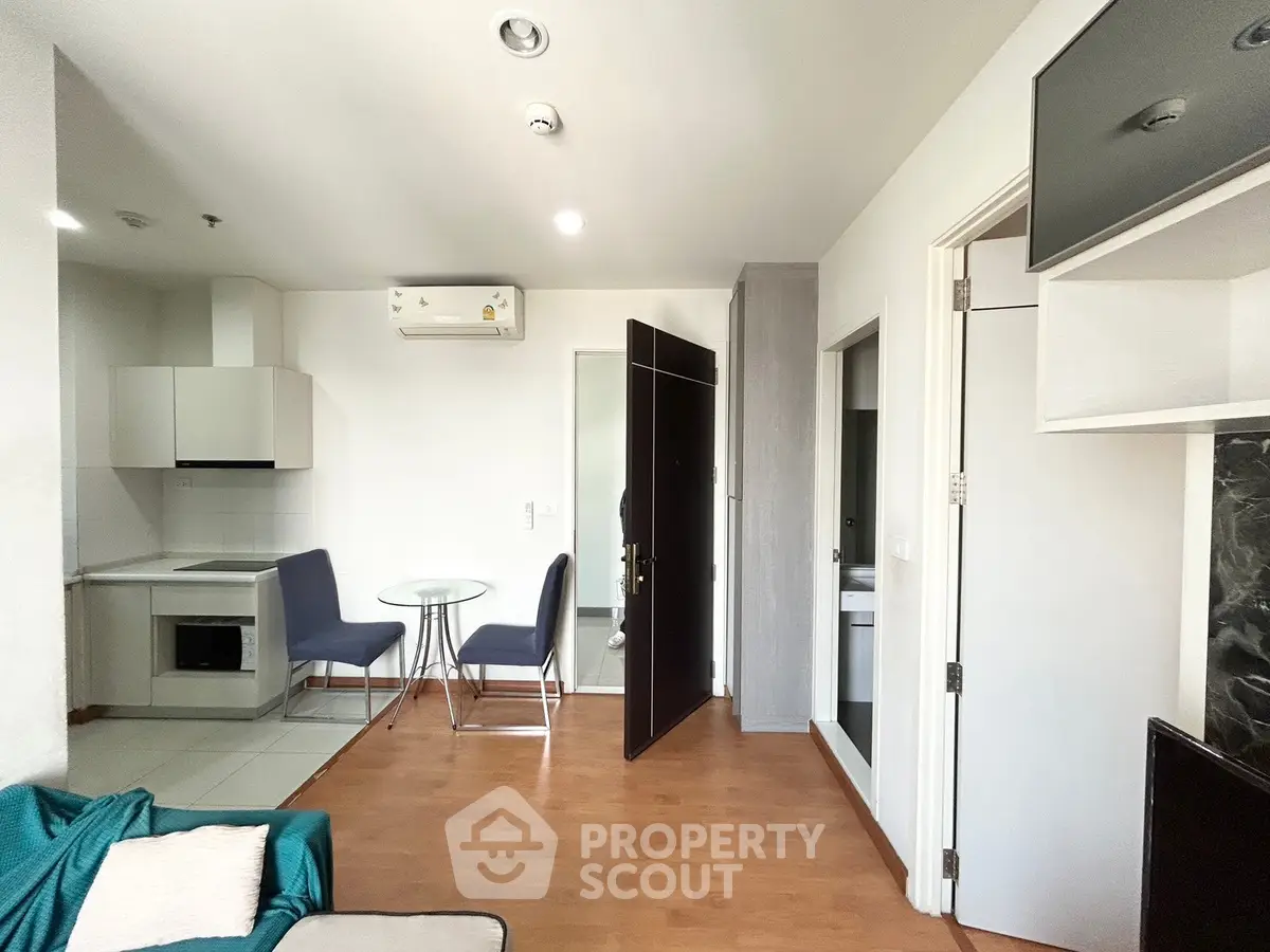 Modern apartment interior with open kitchen and cozy dining area, featuring sleek furniture and wooden flooring.
