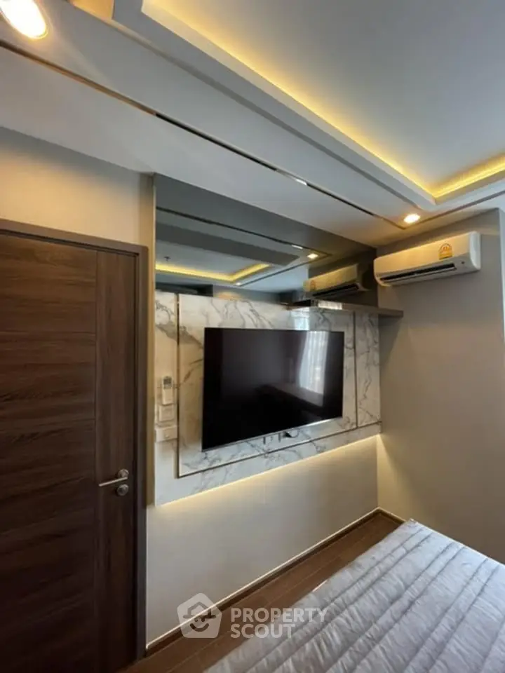 Modern bedroom with sleek design, featuring a wall-mounted TV and ambient lighting.