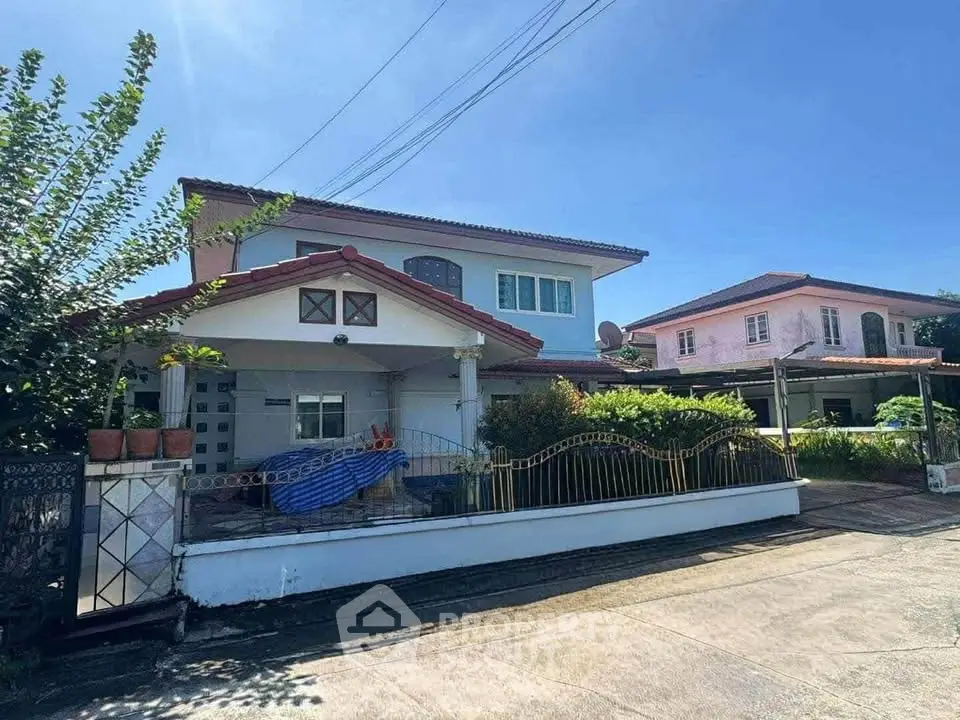 Charming two-story house with spacious driveway and lush greenery in serene neighborhood.