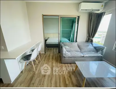 Modern apartment interior with wooden flooring, cozy living area, and bedroom view.