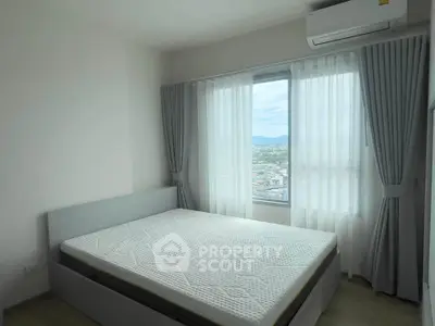Bright bedroom with large window and scenic view, featuring modern air conditioning unit.