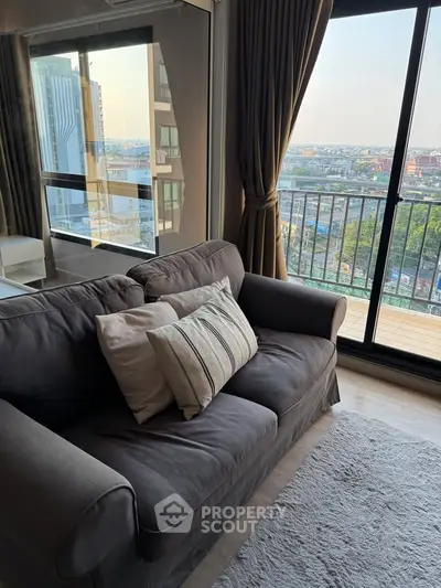 Cozy living room with city view from balcony, featuring a comfortable sofa and stylish decor.