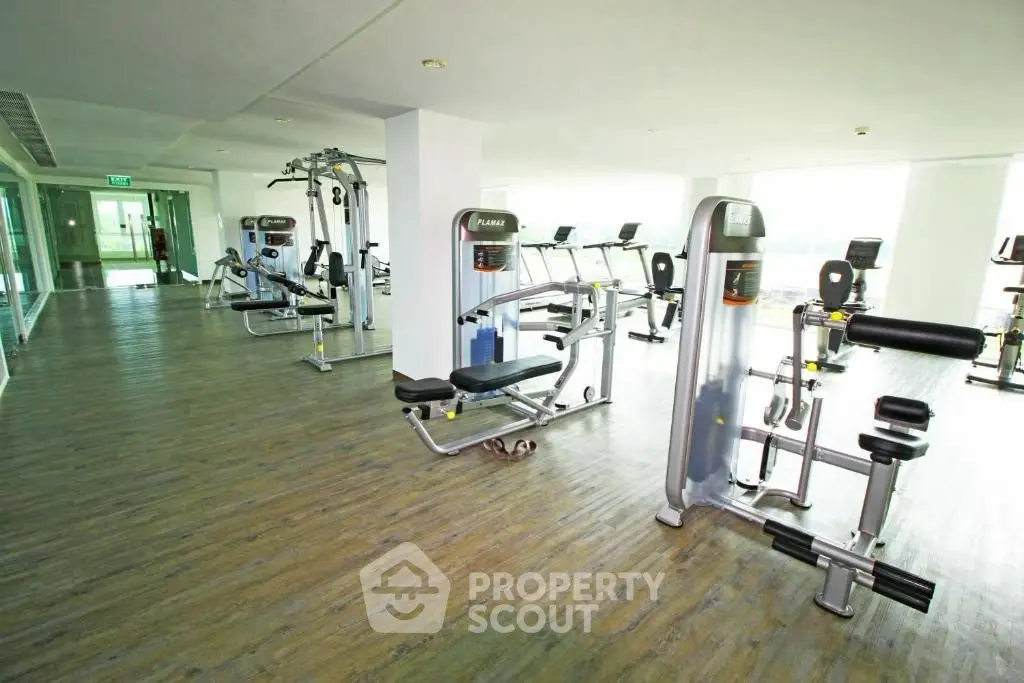 Spacious modern gym with state-of-the-art fitness equipment and bright natural lighting.