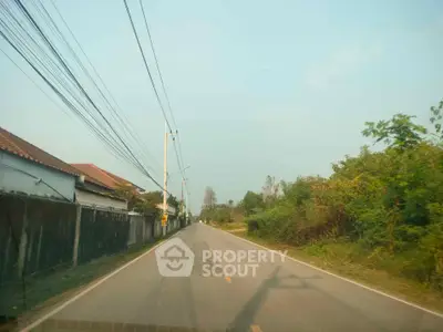Scenic suburban road with houses and lush greenery, perfect for tranquil living.