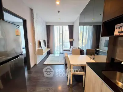 Modern living room with open kitchen and city view, featuring sleek furniture and natural light.