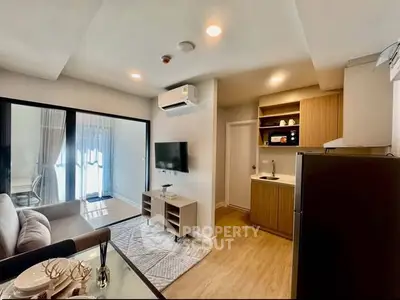 Modern open-plan living room with kitchen, featuring sleek furniture and natural light.