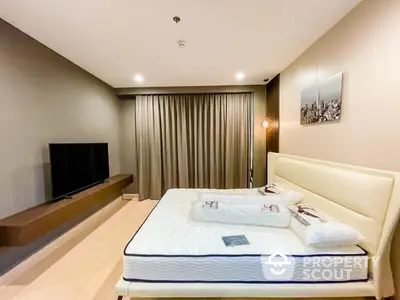 Modern bedroom with stylish decor and large TV, perfect for relaxation.