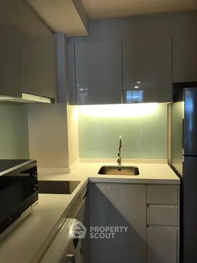 Modern compact kitchen with sleek white cabinets and built-in appliances