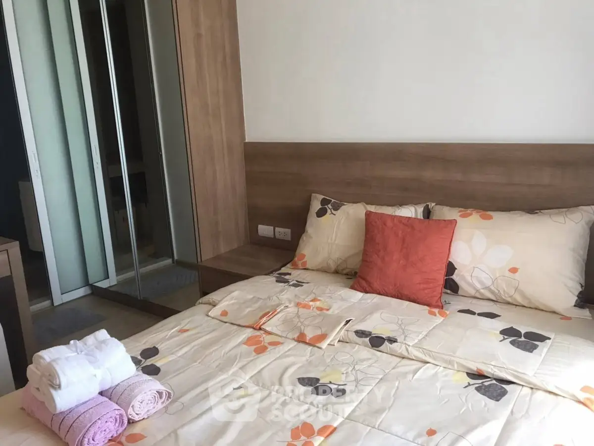 Cozy bedroom with floral bedding and mirrored wardrobe in modern apartment.