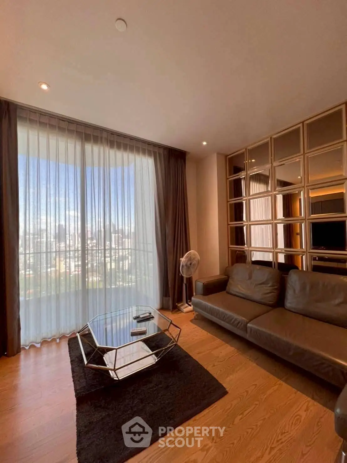 Spacious living room with large window and modern furnishings, offering a stunning city view.