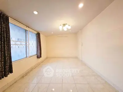 Spacious empty room with large window and elegant lighting, perfect for customization.