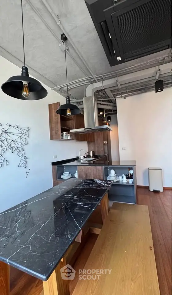Modern kitchen with sleek black marble countertop and industrial lighting, featuring open shelving and wooden accents.