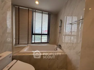 Luxurious bathroom with marble finishes and large window for natural light.