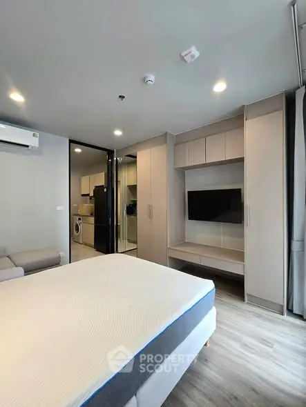 Modern bedroom with sleek design, featuring built-in wardrobe and wall-mounted TV, perfect for urban living.