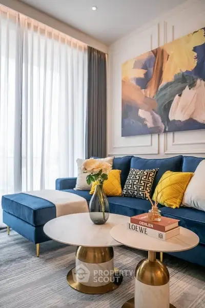 Luxurious living room with modern blue sofa, elegant decor, and stylish coffee tables in a bright, airy space.