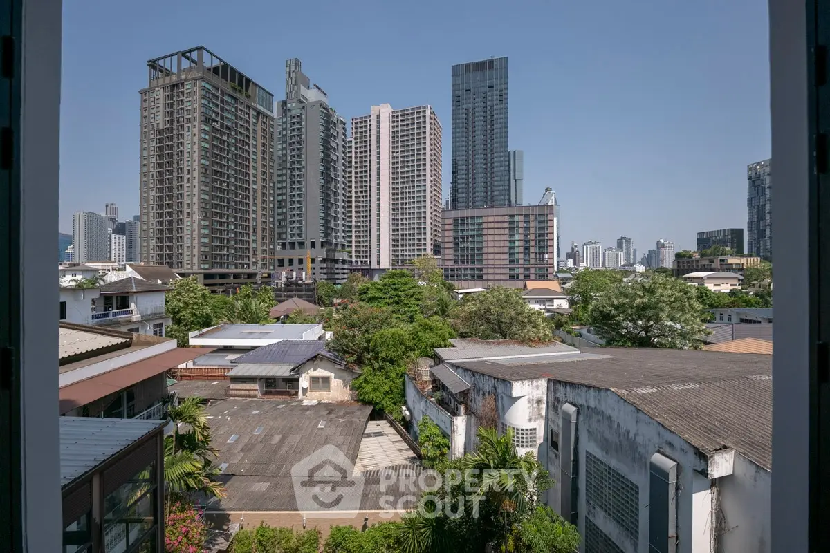 Stunning urban skyline view from a high-rise apartment window, showcasing modern skyscrapers and lush greenery.