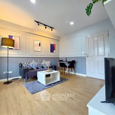 Modern living room with stylish decor and wooden flooring, featuring a cozy seating area and contemporary artwork.