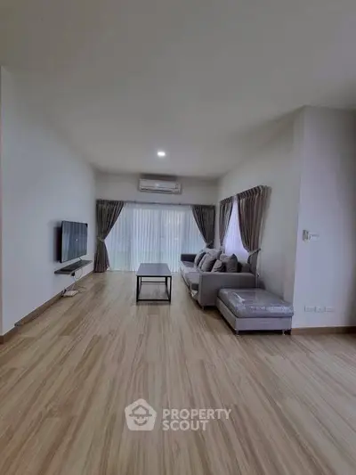 Spacious modern living room with sleek flooring and stylish furniture, perfect for relaxation and entertainment.