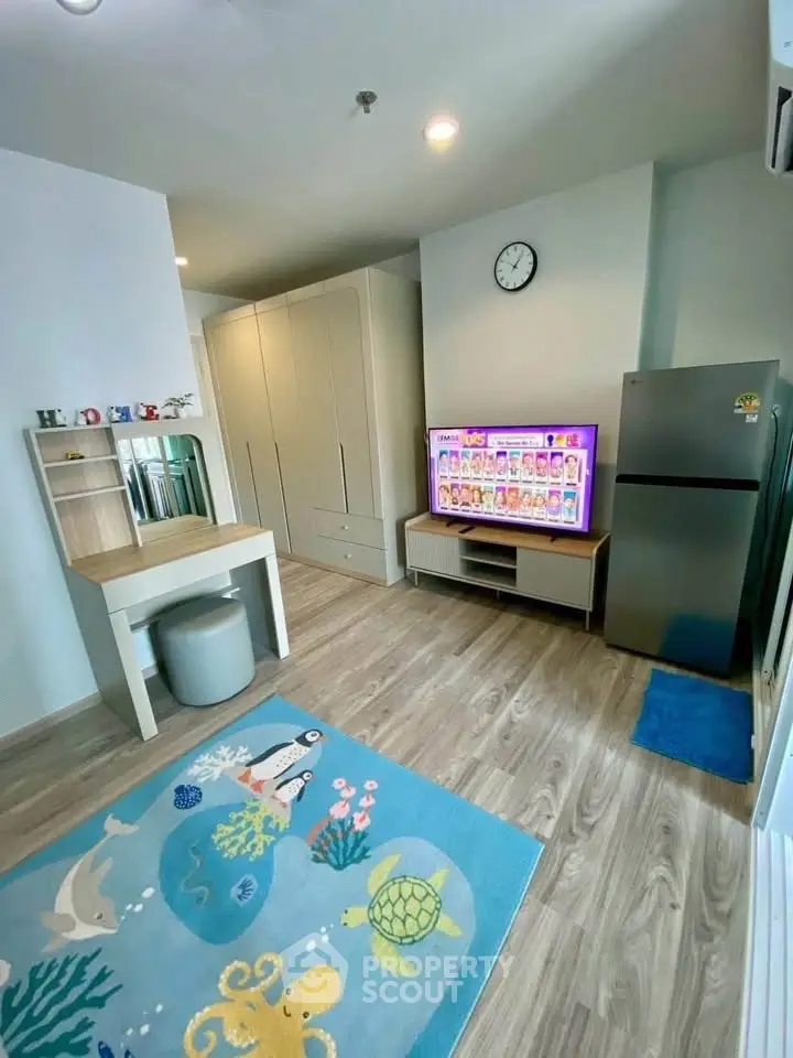 Modern living room with stylish decor, TV, and fridge, featuring a playful ocean-themed rug.