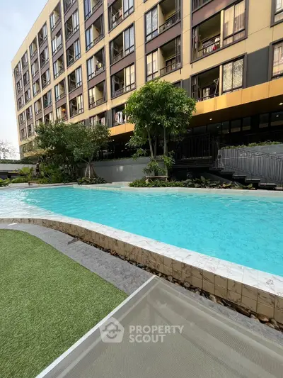 Modern apartment building with a luxurious pool and landscaped garden area.