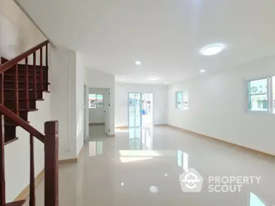 Spacious modern living room with natural light and staircase in a bright home