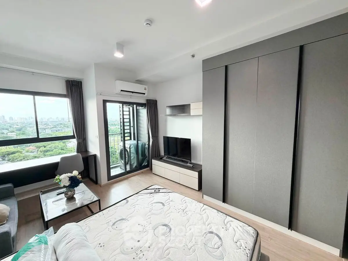 Modern bedroom with large window and balcony offering stunning city views, featuring sleek furniture and ample storage.