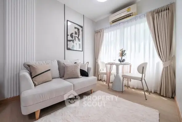 Chic modern living room with cozy sofa, stylish decor, and natural light from large window.