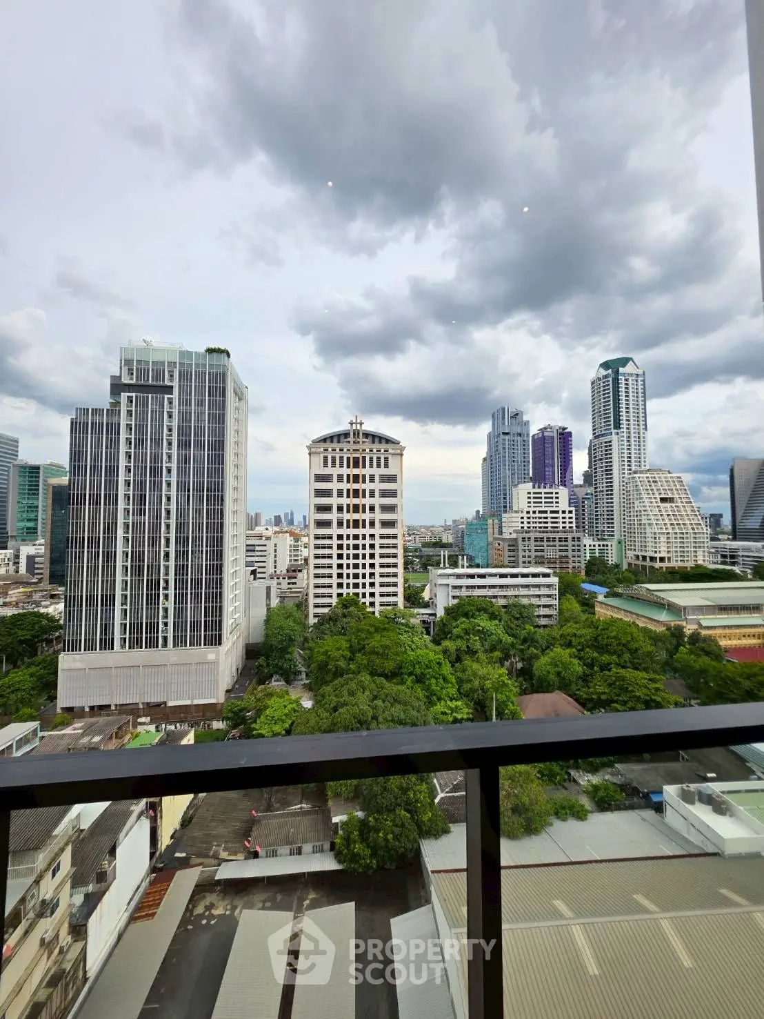 Stunning cityscape view from a high-rise balcony overlooking urban skyline and lush greenery.