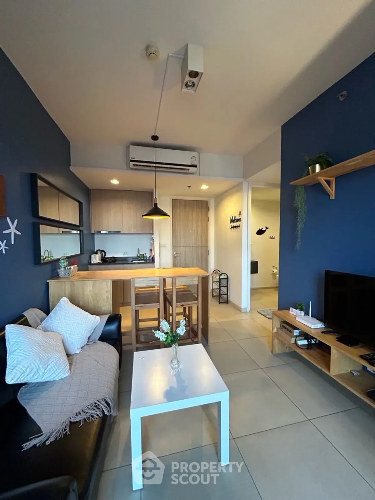 Modern living room with open kitchen, stylish decor, and cozy seating area.
