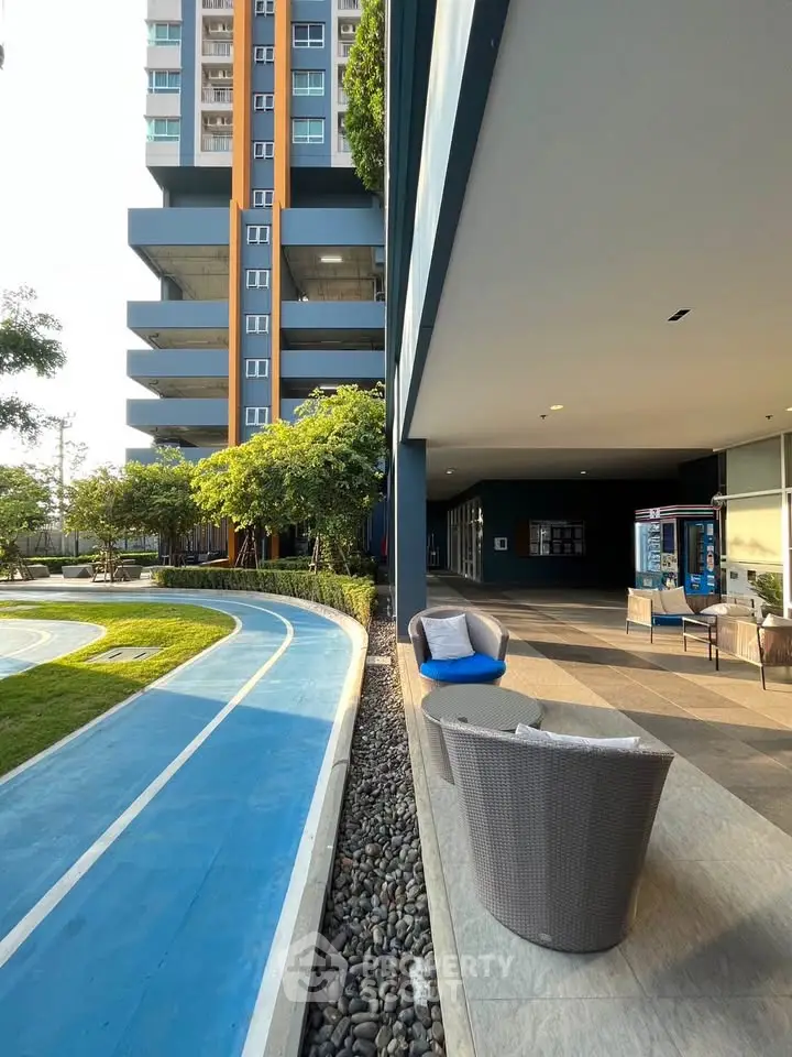 Modern apartment building with outdoor seating and running track, ideal for active lifestyle.