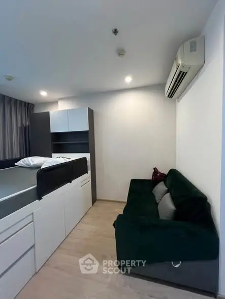Modern studio apartment with built-in bed and cozy sofa, featuring sleek storage solutions.